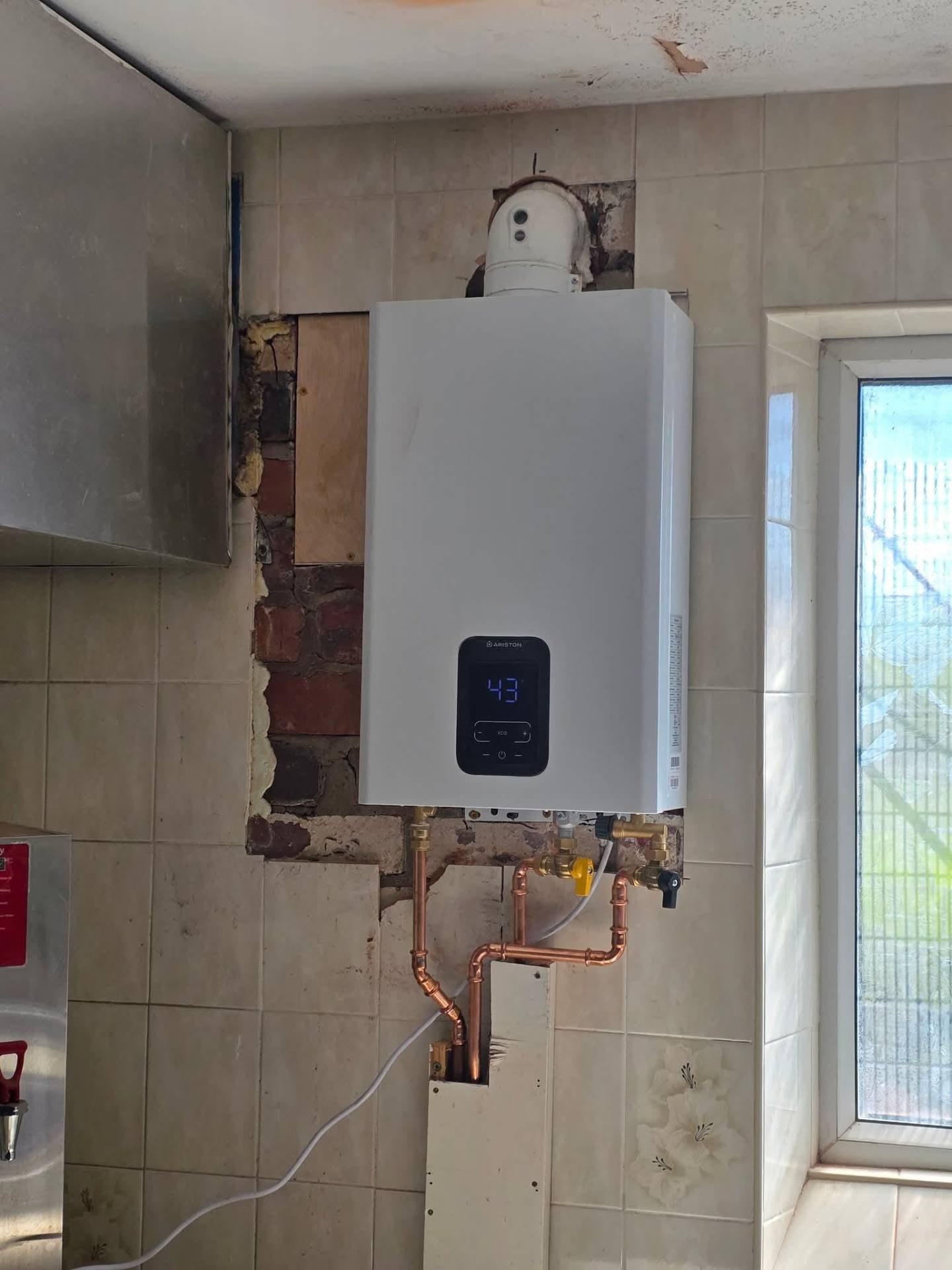 Fresh wall-mounted combi boiler installation with new copper feeds and isolation valves