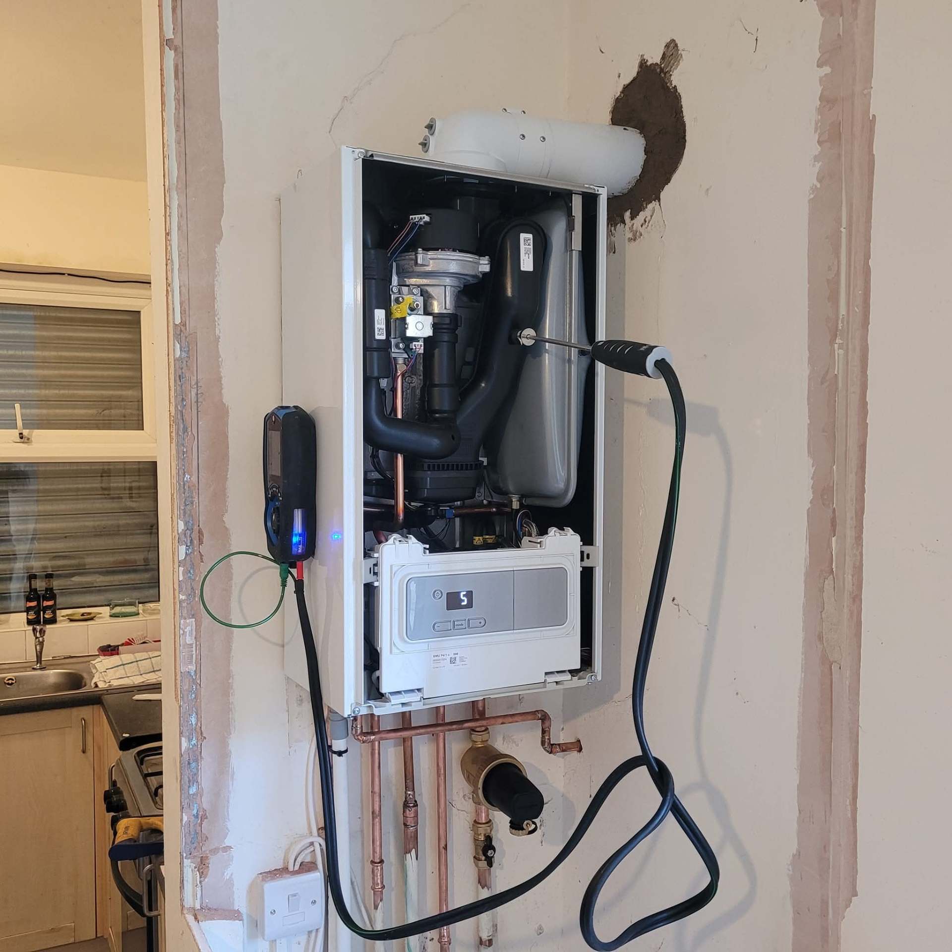Annual boiler service in progress with case removed and combustion analyser checks by Gas Safe engineer
